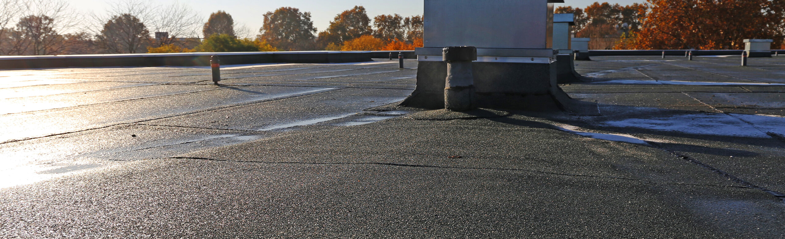 Flat roof with rooftop units and sealed waterproofing details in autumn light